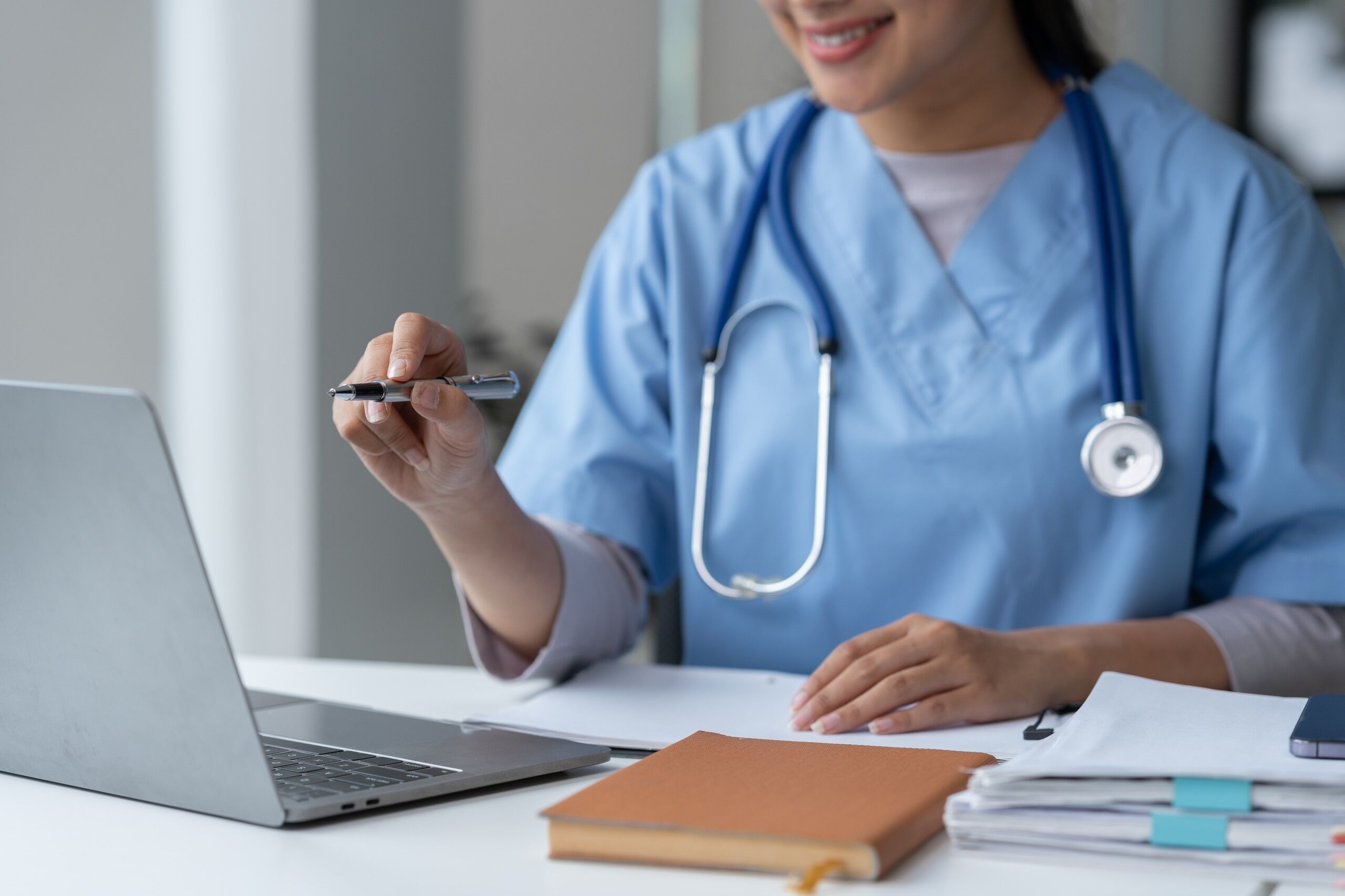 Close up of a female nurse pointing at her laptop with a pen