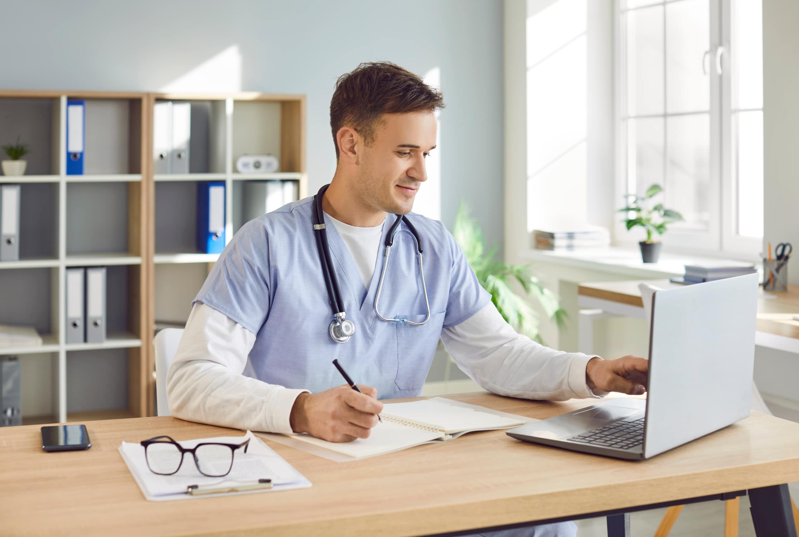 Male nurse smiling and using a laptop