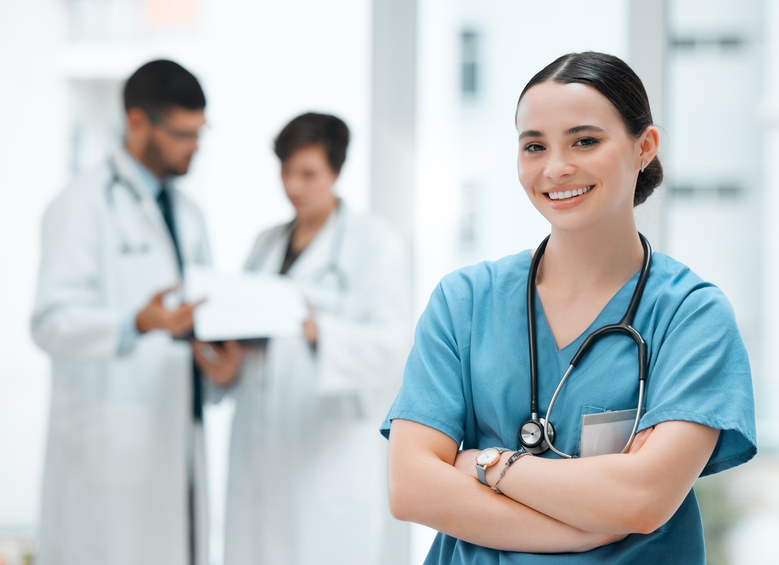 Female nurse with her arms crossed next to other healthcare professionals